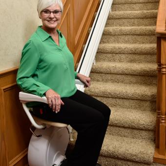 Woman sitting on the Savaria K2 Straight Stair Lift